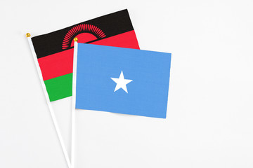 Somalia and Malawi stick flags on white background. High quality fabric, miniature national flag. Peaceful global concept.White floor for copy space.