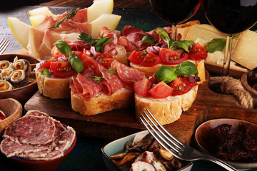 Italian antipasti wine snacks set. Cheese variety, Mediterranean olives, seafood salad, Prosciutto di Parma, tomatoes, anchovy and wine in glasses