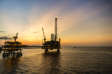 Fototapeta na wymiar Silhouette of oil production platform during sunset
