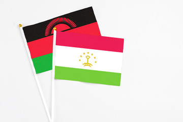 Tajikistan and Malawi stick flags on white background. High quality fabric, miniature national flag. Peaceful global concept.White floor for copy space.