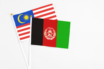 Afghanistan and Malaysia stick flags on white background. High quality fabric, miniature national flag. Peaceful global concept.White floor for copy space.