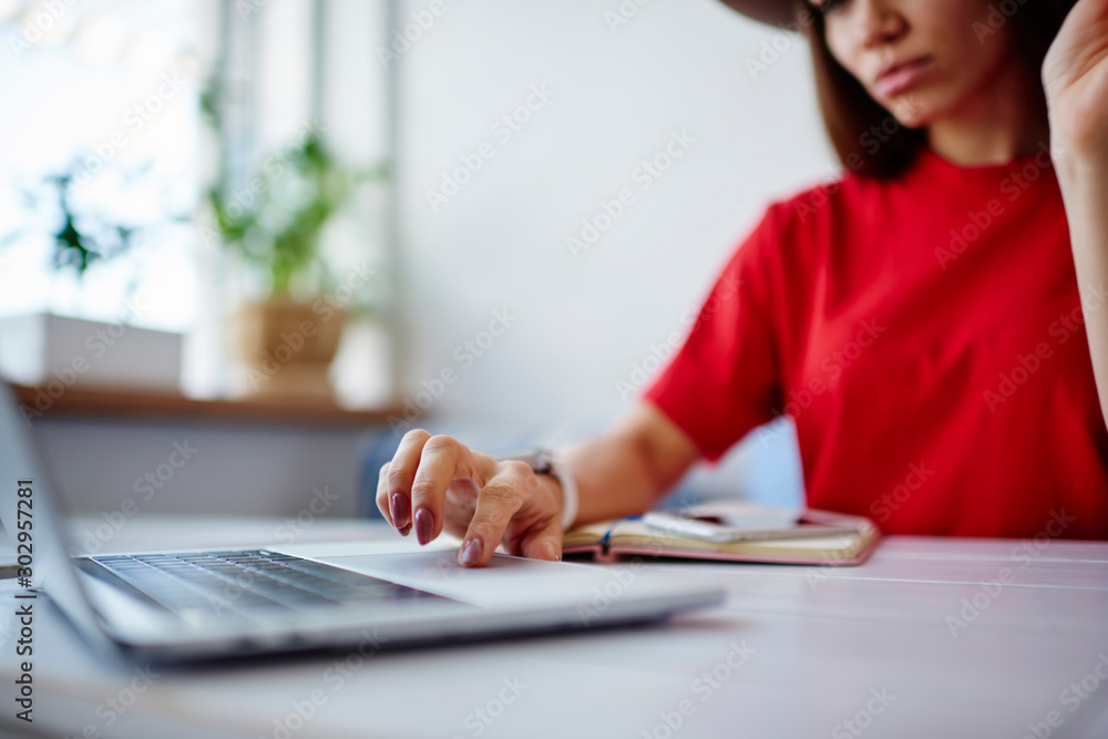 Poster cropped image of female using laptop computer for downloading files from network sitting at desktop,