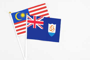 Anguilla and Malaysia stick flags on white background. High quality fabric, miniature national flag. Peaceful global concept.White floor for copy space.