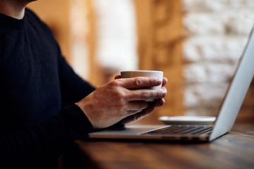 Man with cup of coffee in cafe and laptop