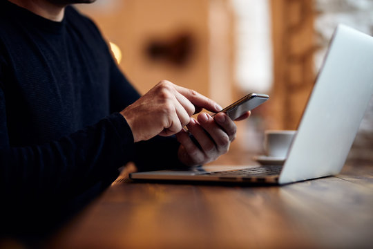 Man using his mobile phone above laptop keyboard - Powered by Adobe