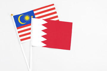 Bahrain and Malaysia stick flags on white background. High quality fabric, miniature national flag. Peaceful global concept.White floor for copy space.