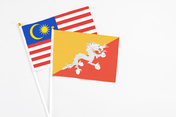 Bhutan and Malaysia stick flags on white background. High quality fabric, miniature national flag. Peaceful global concept.White floor for copy space.