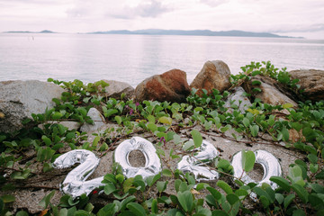 Inflatable silver numbers 2020 on the sand in tropical plants.