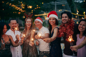 A large company has fun with champagne and sparklers in the tropics.