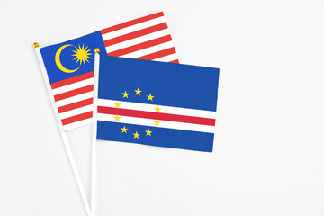 Cape Verde and Malaysia stick flags on white background. High quality fabric, miniature national flag. Peaceful global concept.White floor for copy space.