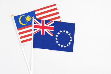 Fototapeta premium Cook Islands and Malaysia stick flags on white background. High quality fabric, miniature national flag. Peaceful global concept.White floor for copy space.