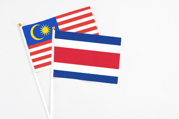 Fototapeta na wymiar Costa Rica and Malaysia stick flags on white background. High quality fabric, miniature national flag. Peaceful global concept.White floor for copy space.