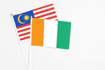 Cote D'Ivoire and Malaysia stick flags on white background. High quality fabric, miniature national flag. Peaceful global concept.White floor for copy space.