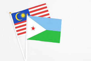 Djibouti and Malaysia stick flags on white background. High quality fabric, miniature national flag. Peaceful global concept.White floor for copy space.