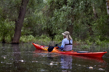 Man in kayak paddle among flooded trees in the forest. Kayaking in wilderness areas at Danube river...