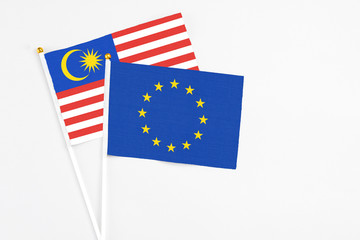 European Union and Malaysia stick flags on white background. High quality fabric, miniature national flag. Peaceful global concept.White floor for copy space.