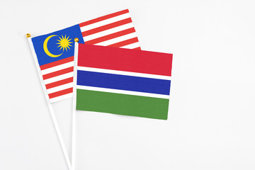 Gambia and Malaysia stick flags on white background. High quality fabric, miniature national flag. Peaceful global concept.White floor for copy space.