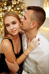couple in love kisses and hugs on the sofa near the Christmas tree lights. New year's night. Christmas.