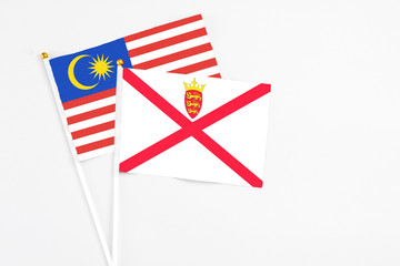 Jersey and Malaysia stick flags on white background. High quality fabric, miniature national flag. Peaceful global concept.White floor for copy space.