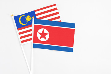 North Korea and Malaysia stick flags on white background. High quality fabric, miniature national flag. Peaceful global concept.White floor for copy space.