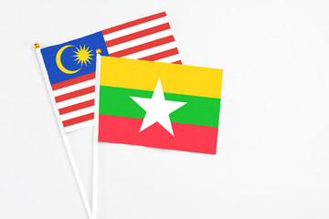 Fototapeta premium Myanmar and Malaysia stick flags on white background. High quality fabric, miniature national flag. Peaceful global concept.White floor for copy space.