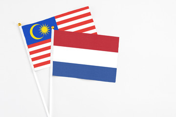 Netherlands and Malaysia stick flags on white background. High quality fabric, miniature national flag. Peaceful global concept.White floor for copy space.