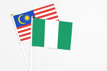 Nigeria and Malaysia stick flags on white background. High quality fabric, miniature national flag. Peaceful global concept.White floor for copy space.