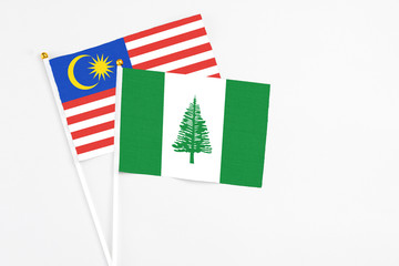 Norfolk Island and Malaysia stick flags on white background. High quality fabric, miniature national flag. Peaceful global concept.White floor for copy space.
