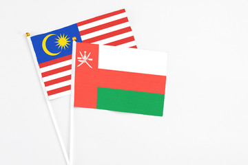 Oman and Malaysia stick flags on white background. High quality fabric, miniature national flag. Peaceful global concept.White floor for copy space.