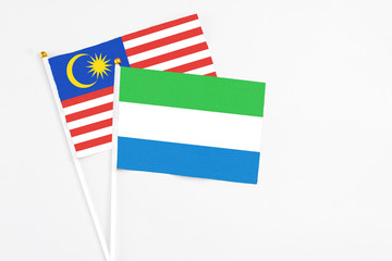 Sierra Leone and Malaysia stick flags on white background. High quality fabric, miniature national...