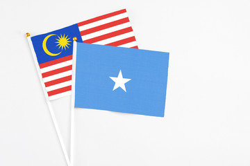 Somalia and Malaysia stick flags on white background. High quality fabric, miniature national flag. Peaceful global concept.White floor for copy space.