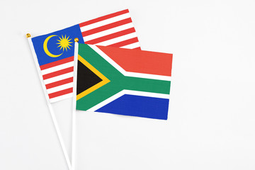South Africa and Malaysia stick flags on white background. High quality fabric, miniature national flag. Peaceful global concept.White floor for copy space.