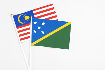 Solomon Islands and Malaysia stick flags on white background. High quality fabric, miniature national flag. Peaceful global concept.White floor for copy space.