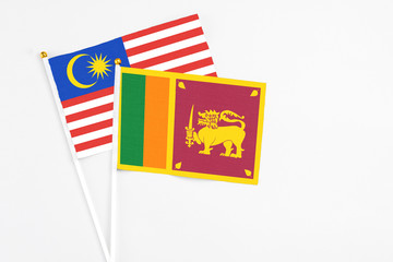 Sri Lanka and Malaysia stick flags on white background. High quality fabric, miniature national flag. Peaceful global concept.White floor for copy space.