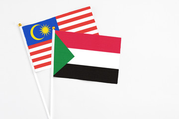 Sudan and Malaysia stick flags on white background. High quality fabric, miniature national flag. Peaceful global concept.White floor for copy space.