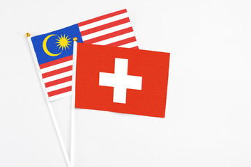 Switzerland and Malaysia stick flags on white background. High quality fabric, miniature national flag. Peaceful global concept.White floor for copy space.