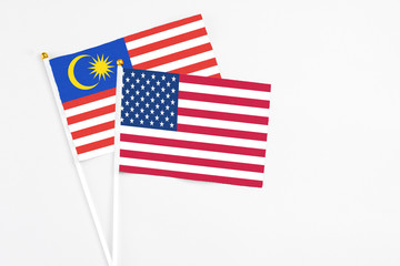 United States and Malaysia stick flags on white background. High quality fabric, miniature national flag. Peaceful global concept.White floor for copy space.