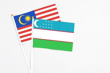 Uzbekistan and Malaysia stick flags on white background. High quality fabric, miniature national flag. Peaceful global concept.White floor for copy space.