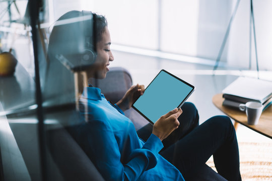 Cheerful adult female watching tablet with blank screen