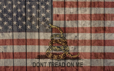 vintage faded american flag and dont tread on me banner painted on the side of a weathered wooden barn