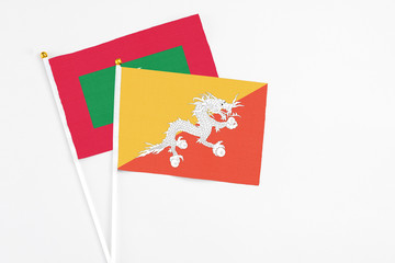 Bhutan and Maldives stick flags on white background. High quality fabric, miniature national flag. Peaceful global concept.White floor for copy space.