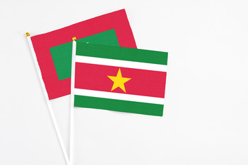 Suriname and Maldives stick flags on white background. High quality fabric, miniature national flag. Peaceful global concept.White floor for copy space.