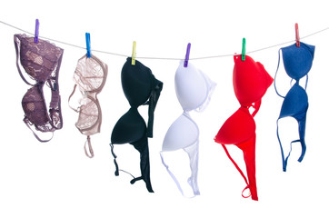 Female bras on clothespins rope on white background isolation - obrazy, fototapety, plakaty