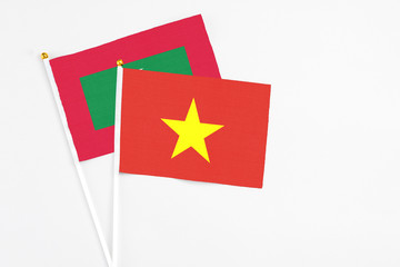 Vietnam and Maldives stick flags on white background. High quality fabric, miniature national flag. Peaceful global concept.White floor for copy space.