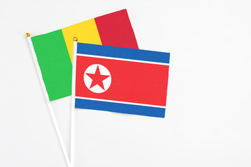 North Korea and Mali stick flags on white background. High quality fabric, miniature national flag. Peaceful global concept.White floor for copy space.