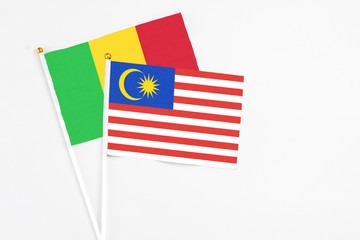 Malaysia and Mali stick flags on white background. High quality fabric, miniature national flag. Peaceful global concept.White floor for copy space.