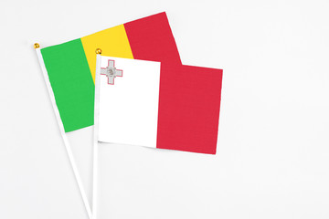 Malta and Mali stick flags on white background. High quality fabric, miniature national flag. Peaceful global concept.White floor for copy space.