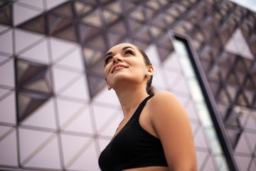 Young woman dressed black sportweart trainig workout outdoors against the street wall.  Style girl do morning activity exercise