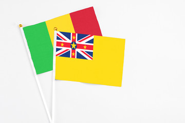 Niue and Mali stick flags on white background. High quality fabric, miniature national flag. Peaceful global concept.White floor for copy space.