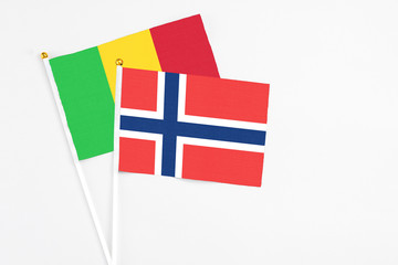Obraz premium Norway and Mali stick flags on white background. High quality fabric, miniature national flag. Peaceful global concept.White floor for copy space.